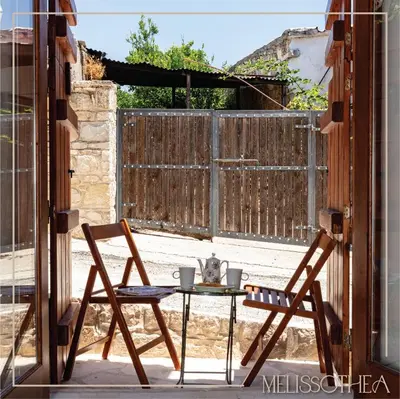 a table and chairs on a patio with a fence at Melissothea Stone Suites in Mesana