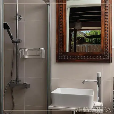 a bathroom with a sink and a mirror and a shower at Melissothea Stone Suites in Mesana