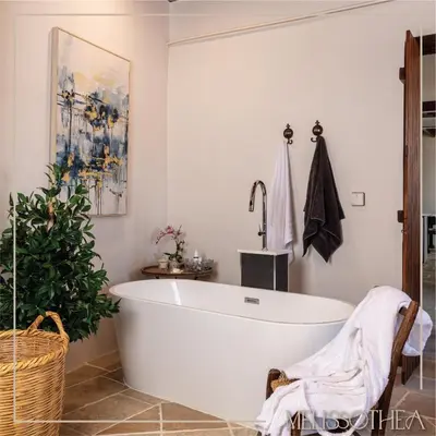 a white bath tub in a bathroom with a plant at Melissothea Stone Suites in Mesana