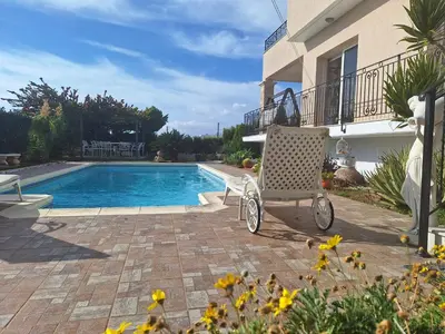 a chair sitting on a patio next to a swimming pool at ROSE VILLA - 3 BED POOL in Episkopi Lemesou