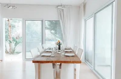 a dining room with a wooden table and white chairs at Wealthystays Niceday Hill Villa in Protaras