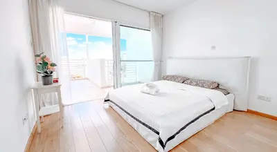 a white bedroom with a bed and a large window at Wealthystays Niceday Hill Villa in Protaras
