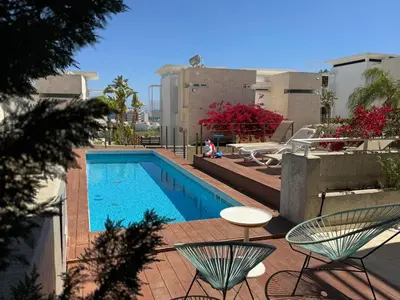 a swimming pool with chairs and a table on a patio at Wealthystays Niceday Hill Villa in Protaras