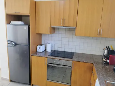 a kitchen with wooden cabinets and a stainless steel refrigerator at Beach bliss apartment in Protaras