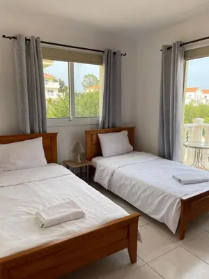 two beds in a room with two windows at Villa Rhea in Ayia Napa