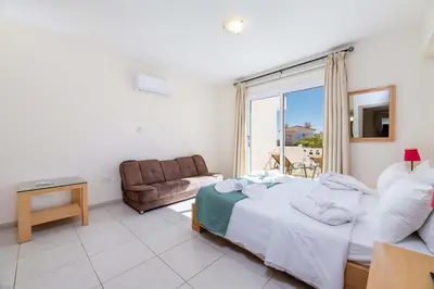 a bedroom with a bed and a couch and a window at Estelle Suite in Ayia Napa
