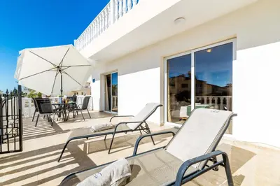 a patio with chairs and an umbrella on a deck at Estelle Suite in Ayia Napa