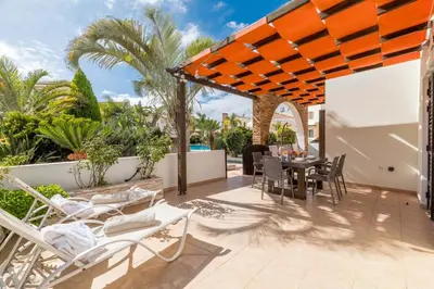 a patio with a table and chairs and palm trees at Villa Anna Maria in Ayia Napa