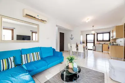 a living room with a blue couch and a kitchen at Villa Anna Maria in Ayia Napa