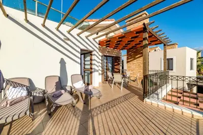 a deck with chairs and a pergola at Villa Anna Maria in Ayia Napa