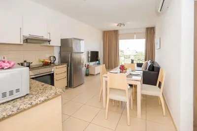 a kitchen and dining room with a table and chairs at Austin - Coralli Beachfront Apartment in Protaras