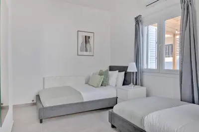 a white bedroom with two beds and a window at Phaedrus Living: Luxury Residence Faneromeni in Larnaka