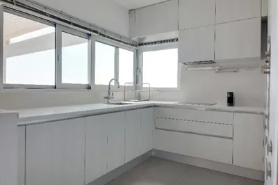 a white kitchen with white cabinets and windows at Phaedrus Living: Beach Front Flat Kyma in Limassol
