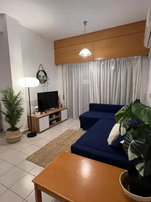 a living room with a blue couch and a tv at Makenzie 2 rooms first line beach in Larnaka