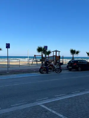 a motorcycle parked on the side of a road near the beach at Makenzie 2 rooms first line beach in Larnaka