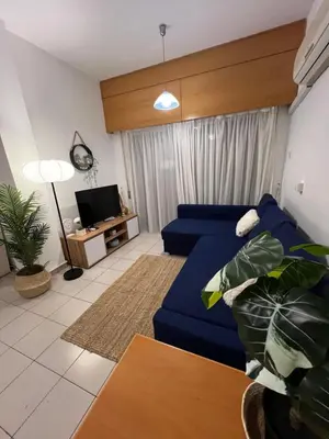 a living room with a blue couch and a tv at Makenzie 2 rooms first line beach in Larnaka