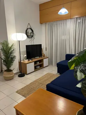 a living room with a blue couch and a tv at Makenzie 2 rooms first line beach in Larnaka