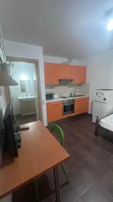 a kitchen with a table and a kitchen with orange cabinets at Lovely studio in Makedonitissa in Nicosia