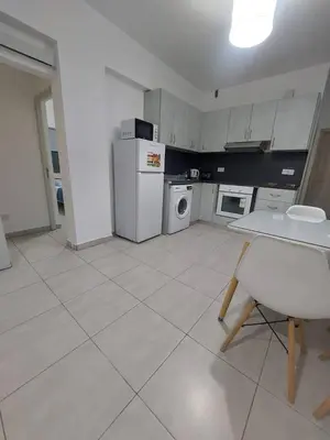 a kitchen with a table and a white refrigerator at One bedroom city centre in Larnaka