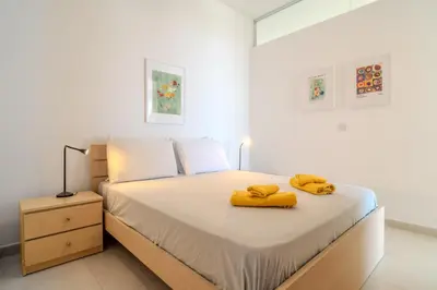 a bedroom with a bed with yellow towels on it at Amazing Sea and Marina View City Center 2BDR Flat in Larnaka