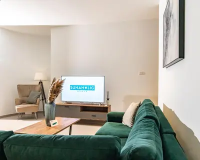 a living room with a green couch and a tv at Venus Apartment in Larnaka