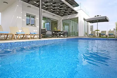 a swimming pool with chairs and a house at Villa Napa Blu in Ayia Napa