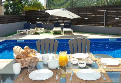 a table with plates of food next to a swimming pool at Villa Argyro in Ayia Napa