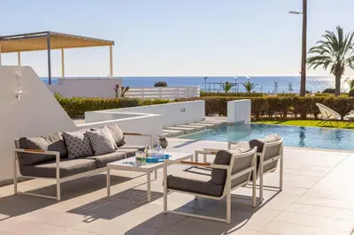 a patio with a couch and chairs next to a pool at Protaras Elaia Luxury Seafront Villa in Protaras