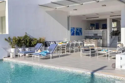 a patio with chairs and a table and a pool at Protaras Elaia Luxury Seafront Villa in Protaras
