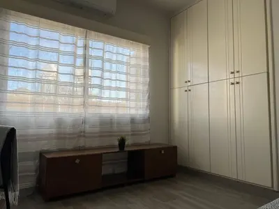 a living room with a dresser and a large window at Quiet place in Limassol