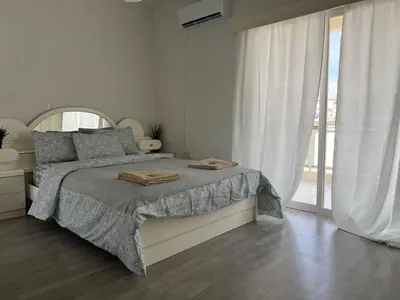 a white bedroom with a bed and a large window at Quiet place in Limassol