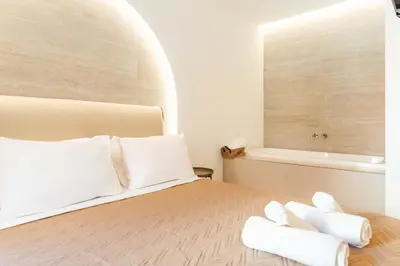 a bedroom with a bed with white pillows and a tub at The Secret Yard in Larnaka
