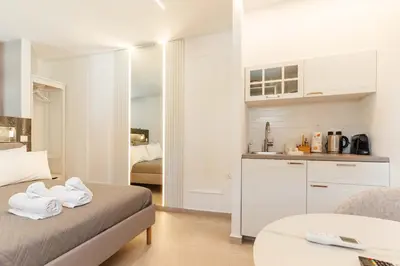 a white room with a bed and a kitchen at The Secret Yard in Larnaka