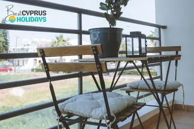 a wooden chair with a plant on a balcony at Blue Touch Pervolia Paradise near the beach in Larnaka
