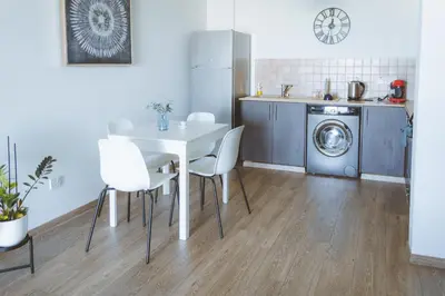 a kitchen with a table and chairs and a washing machine at Blue Touch Pervolia Paradise near the beach in Larnaka