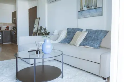 a living room with a couch and a glass table at Blue Touch Pervolia Paradise near the beach in Larnaka
