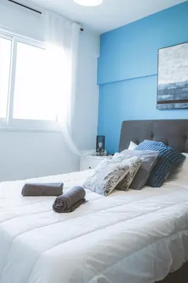 a bedroom with a large white bed with blue walls at Blue Touch Pervolia Paradise near the beach in Larnaka