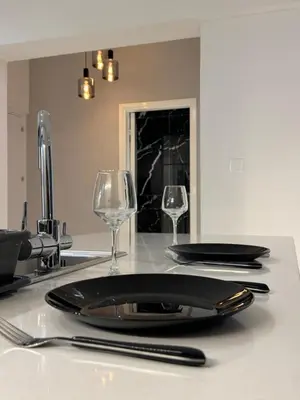 a table with a black plate and two wine glasses at Spacious 1 bedroom flat in Foinikoudes! in Larnaka