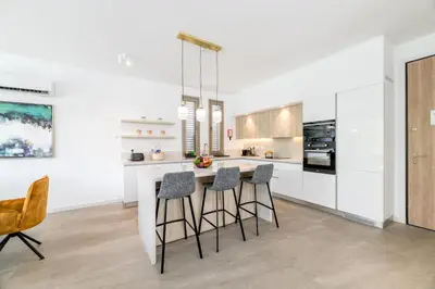 a kitchen with white cabinets and bar stools at Azure Seaview - Ruby Villa in Protaras