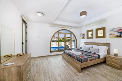 a bedroom with a bed and a desk and a window at Kymma Villa #5 in Ayia Napa