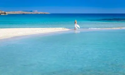 a woman walking on a beach in the water at Kymma Villa #5 in Ayia Napa
