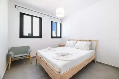 a bedroom with a bed and a chair and windows at By The Beach - Blue Topaz Villa in Protaras