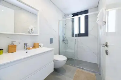 a white bathroom with a shower and a toilet at By The Beach - Blue Topaz Villa in Protaras