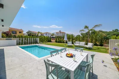 a patio with a table and chairs next to a pool at By The Beach - Blue Topaz Villa in Protaras
