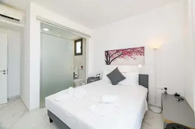 a white bedroom with a large white bed and a bathroom at By The Beach - Emerald Seaview Villa in Protaras