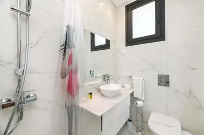 a white bathroom with a sink and a shower at By The Beach - Emerald Seaview Villa in Protaras