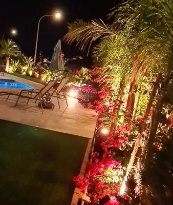 a resort pool with chairs and flowers at night at By The Beach - Emerald Seaview Villa in Protaras