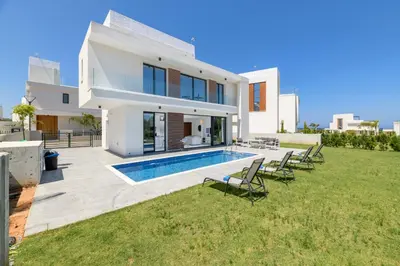 a villa with a swimming pool and lawn at By The Beach - White Coral Villa in Protaras