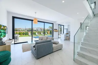 a living room with a couch and a stair case at By The Beach - White Coral Villa in Protaras