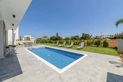a villa with a swimming pool and a yard at By The Beach - White Coral Villa in Protaras